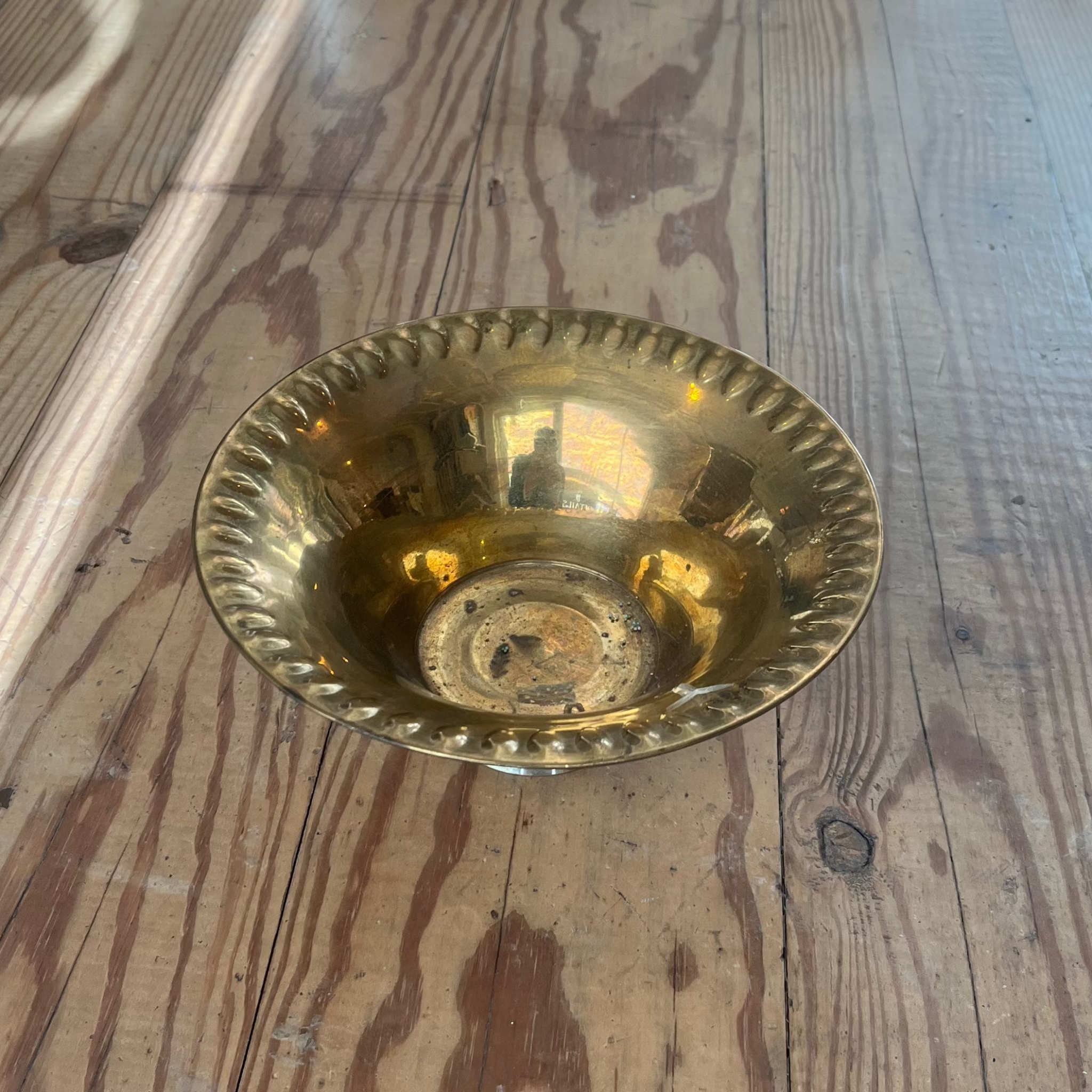 brass footed bowl with decorative edge.