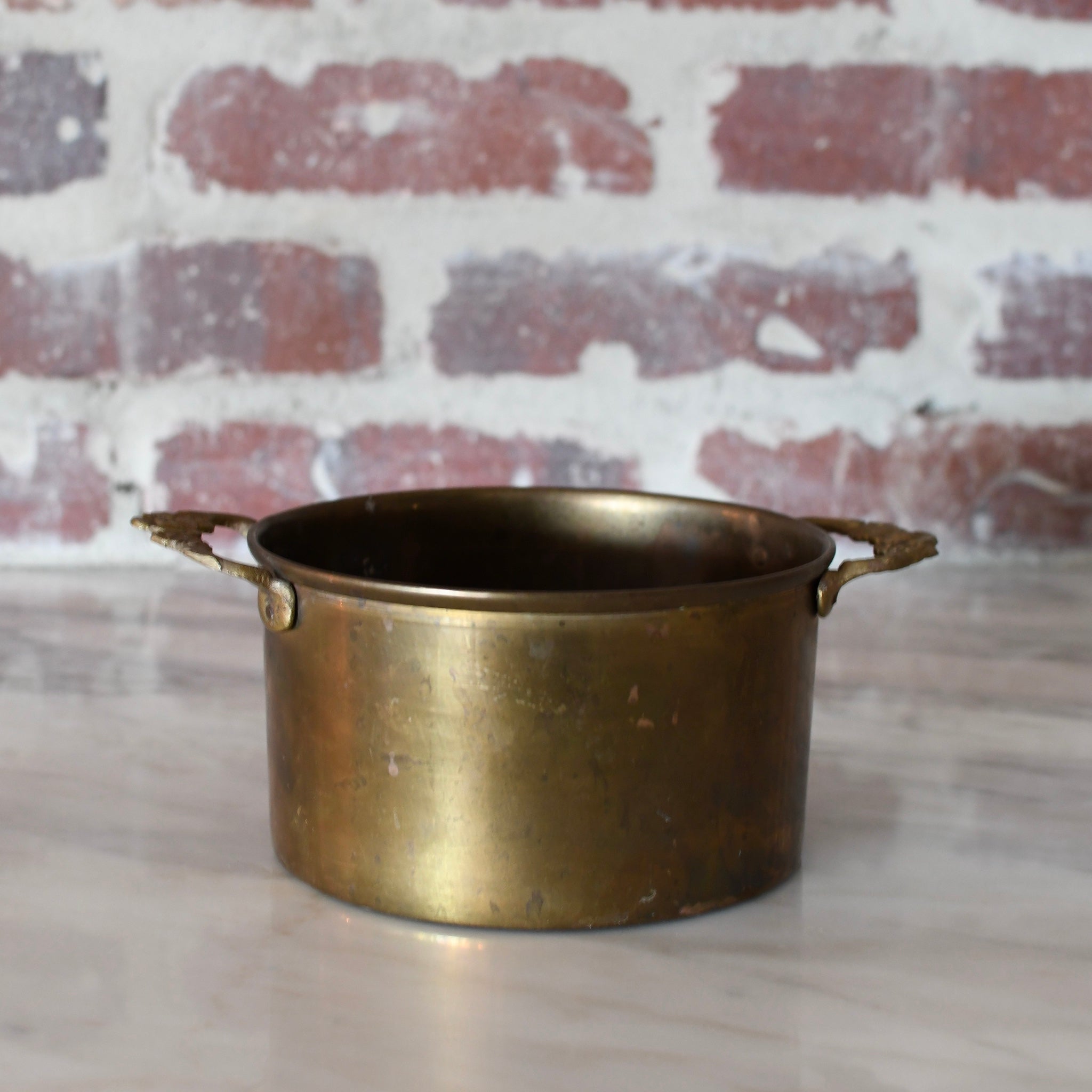 brass pot with decorative floral handles.