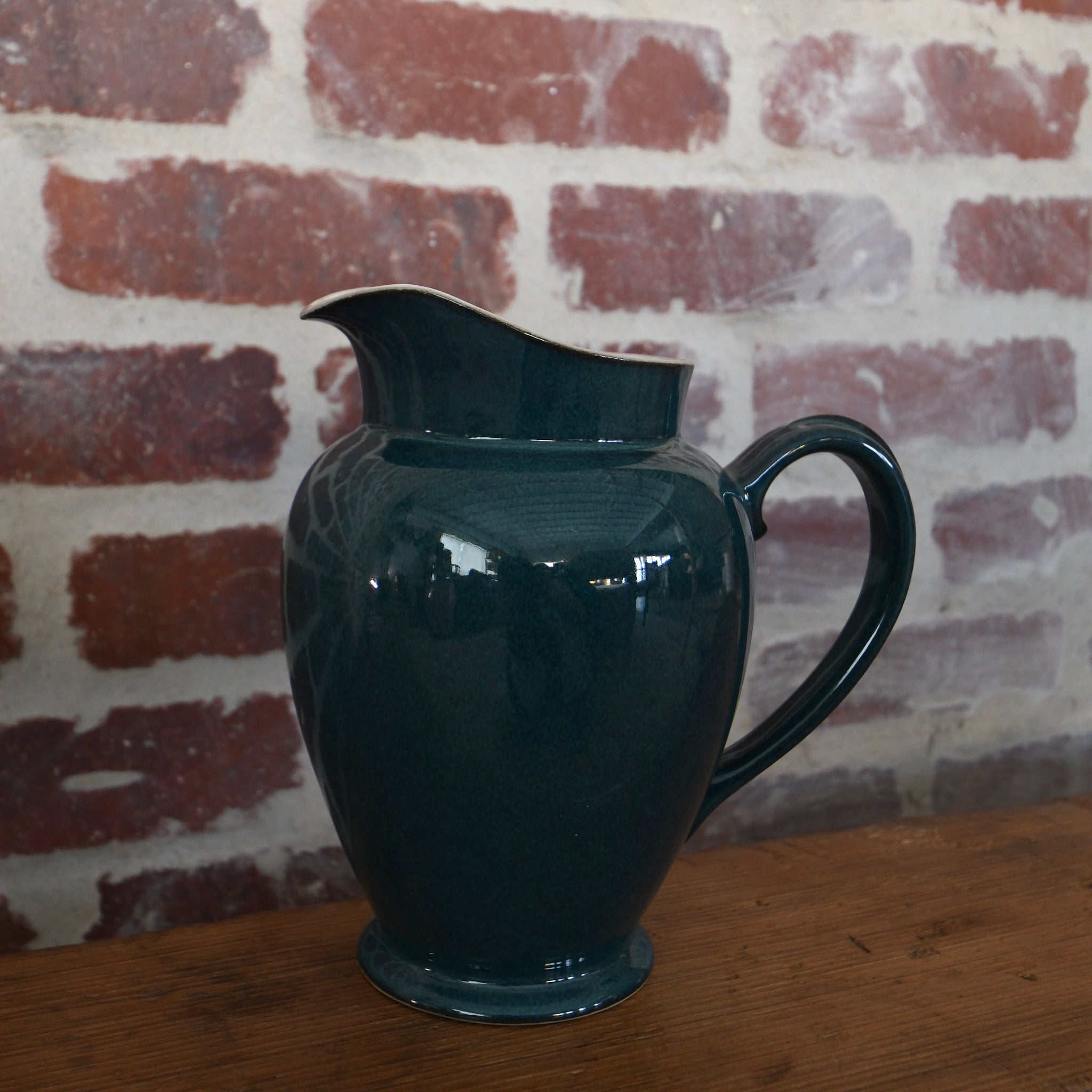 Antique teal green ceramic pitcher with graceful form and subtle patina, embodying elegance and refined craftsmanship.