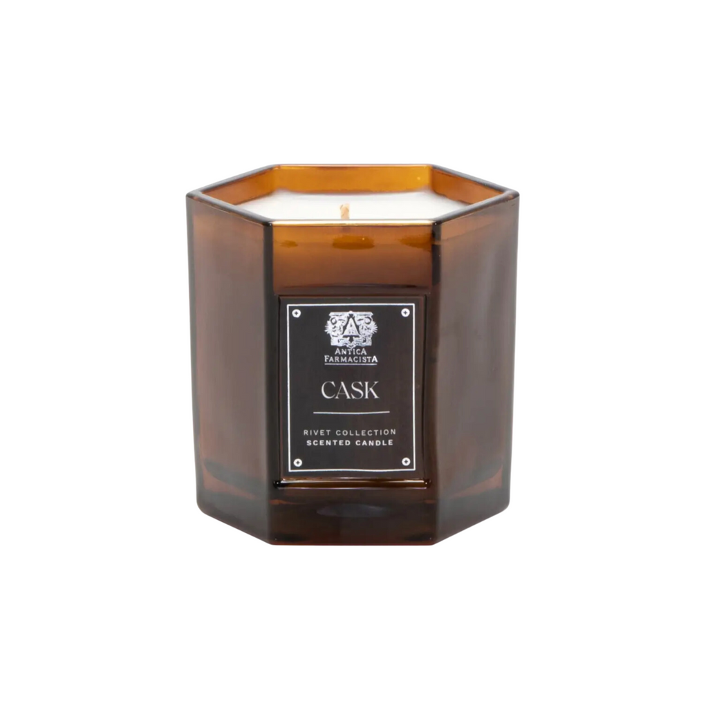 Antica Farmacista Cask 9oz Candle with lit wick, placed in soft white hexagonal glass