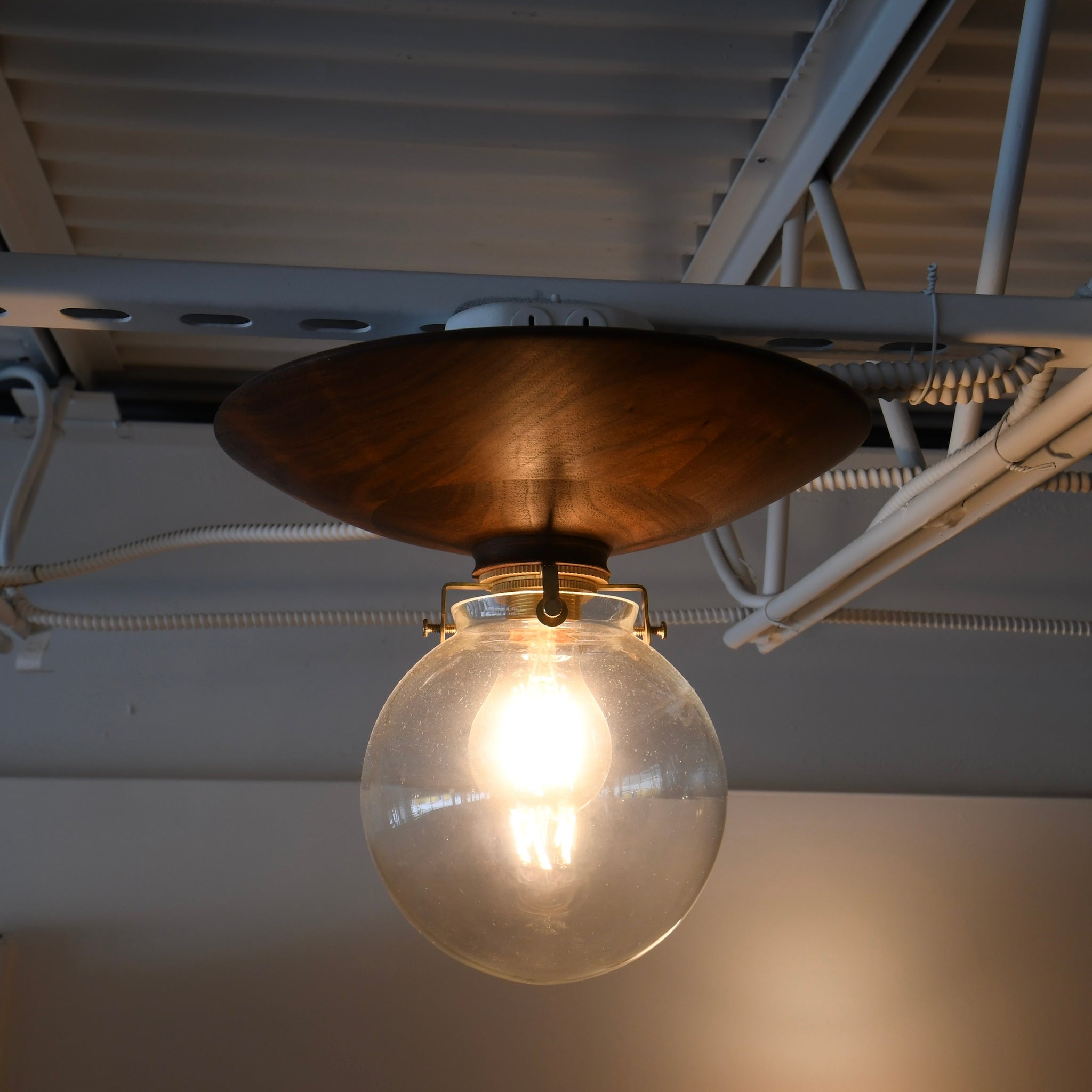 Transitional and industrial ceiling fixture – glass globe and warm wood design.