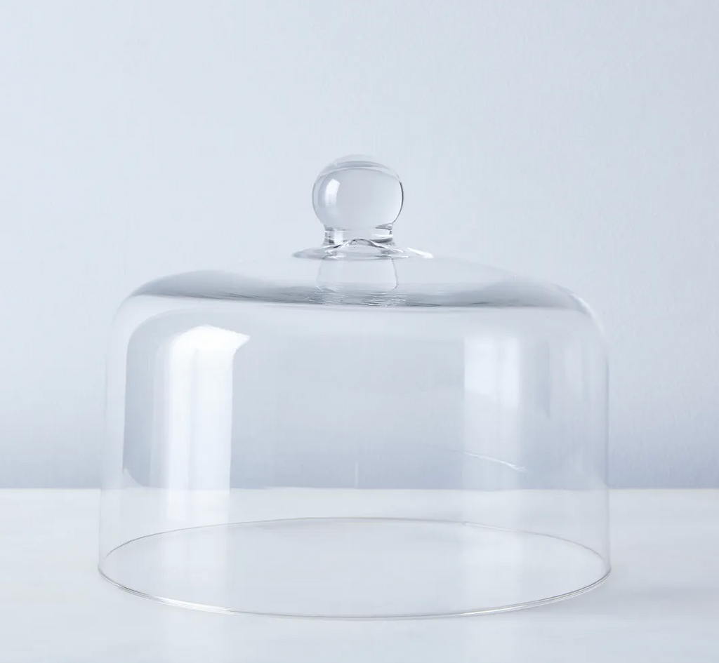 An Elegant 12" Hand-Blown Glass Cake Dome by Mosser Glass rests on a white surface against a gray background, promising an elevated dining experience.