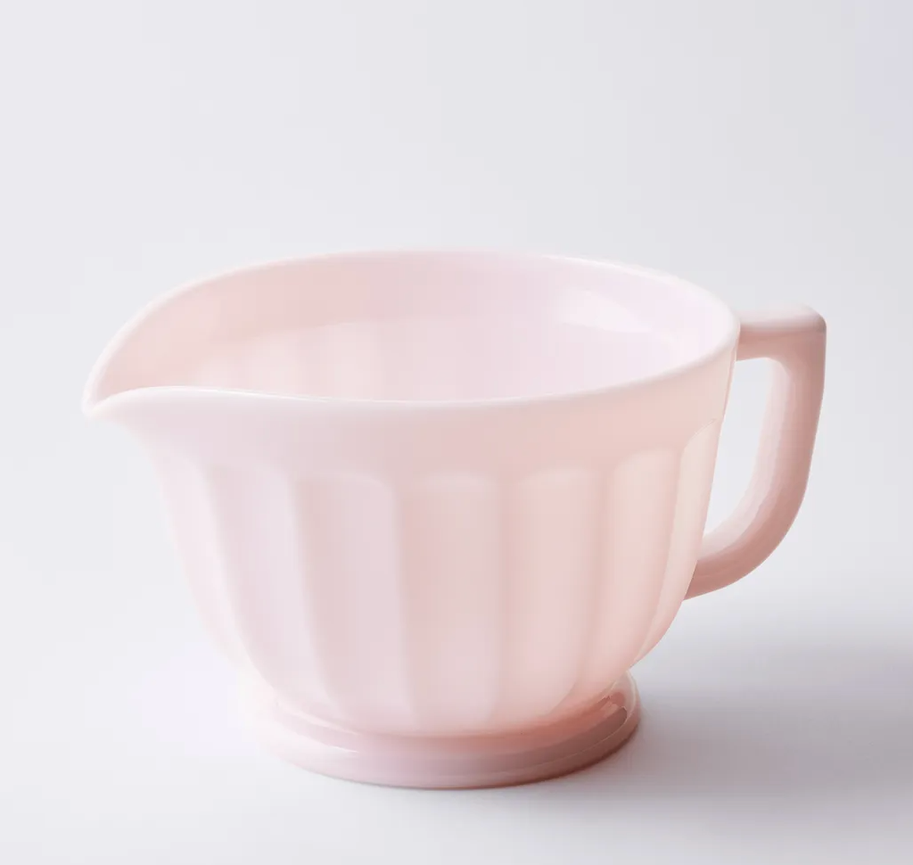 A pink ceramic measuring cup with vintage charm against a white background.