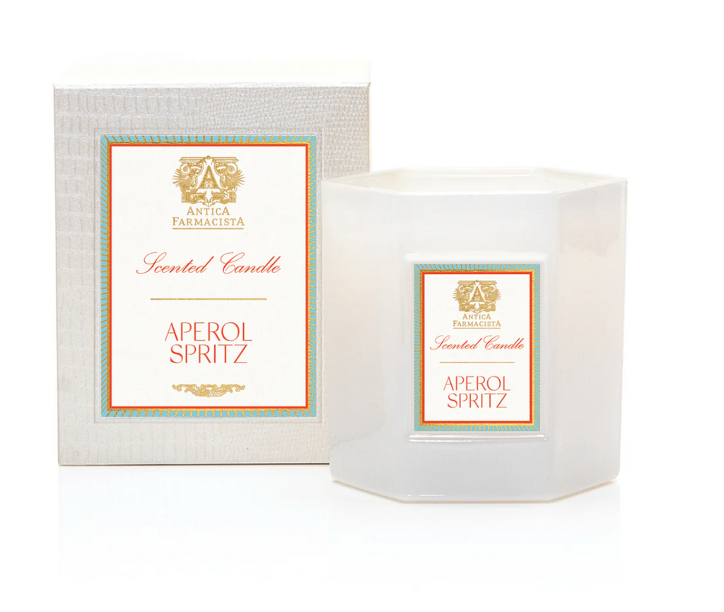 Aperol Spritz Candle with lit wick, placed in soft white hexagonal glass