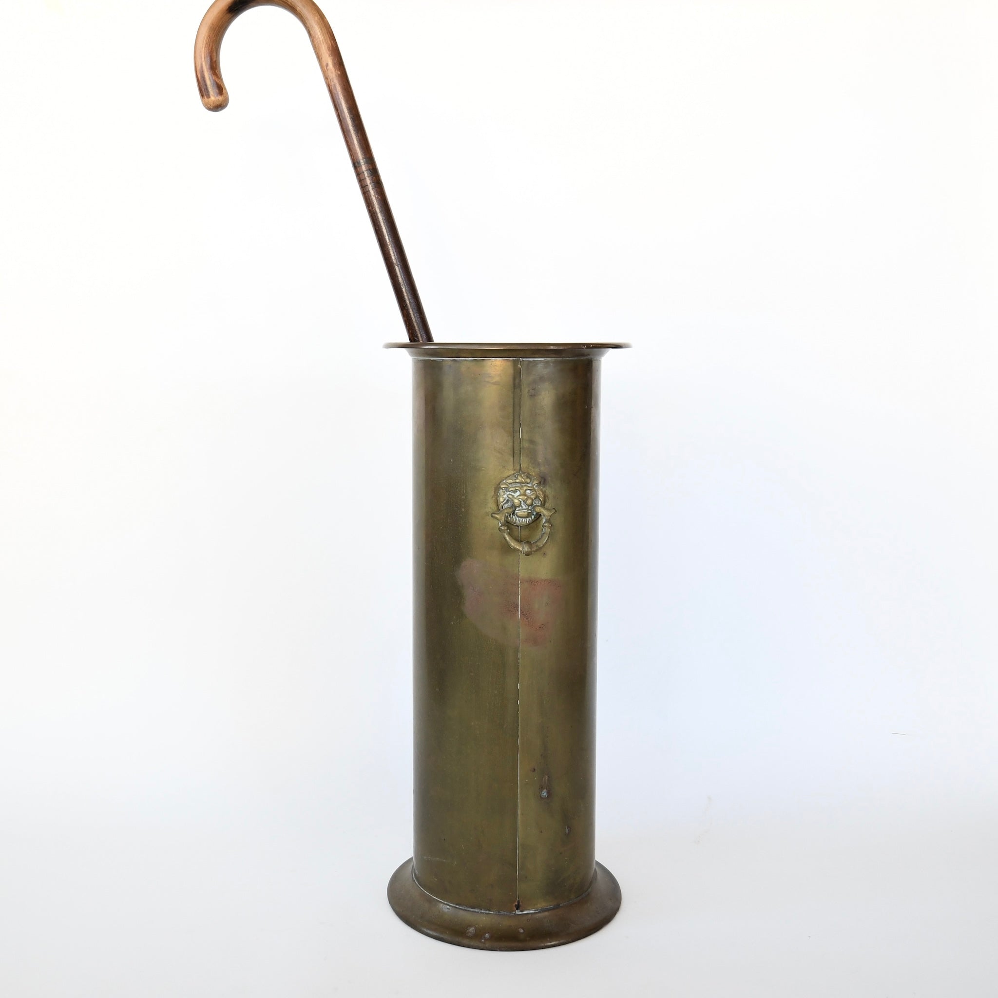 Sophisticated antique brass umbrella stand in mud room.