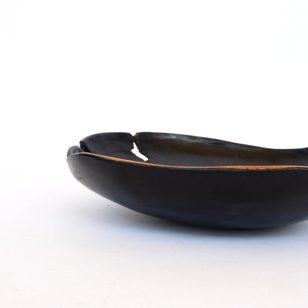 A chipped Black Texture Bowl by Golden Oldies on a white background is replaced by a hand-made wooden bowl in its natural shape.