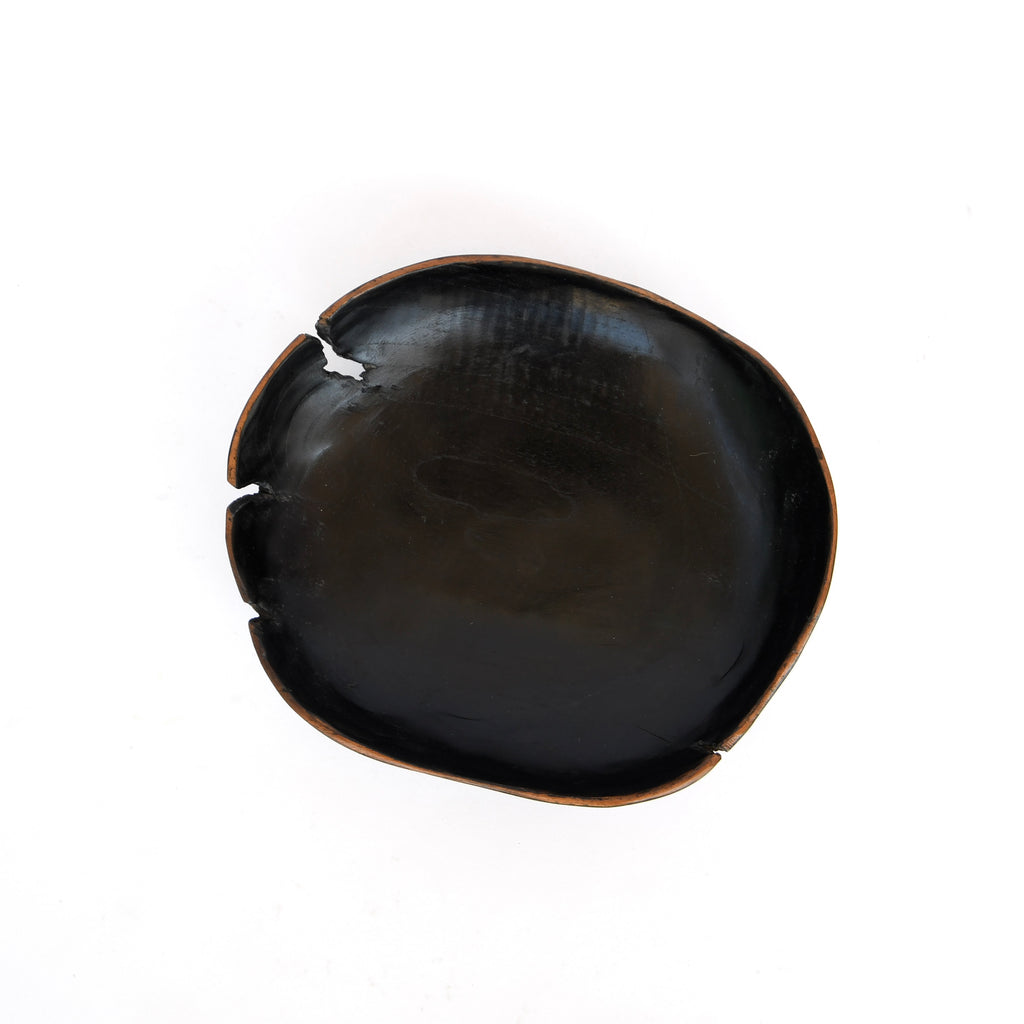 A Golden Oldies black texture bowl with a chip on the edge, photographed against a white background, has a natural shape.