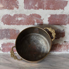 brass pot with decorative floral handles.