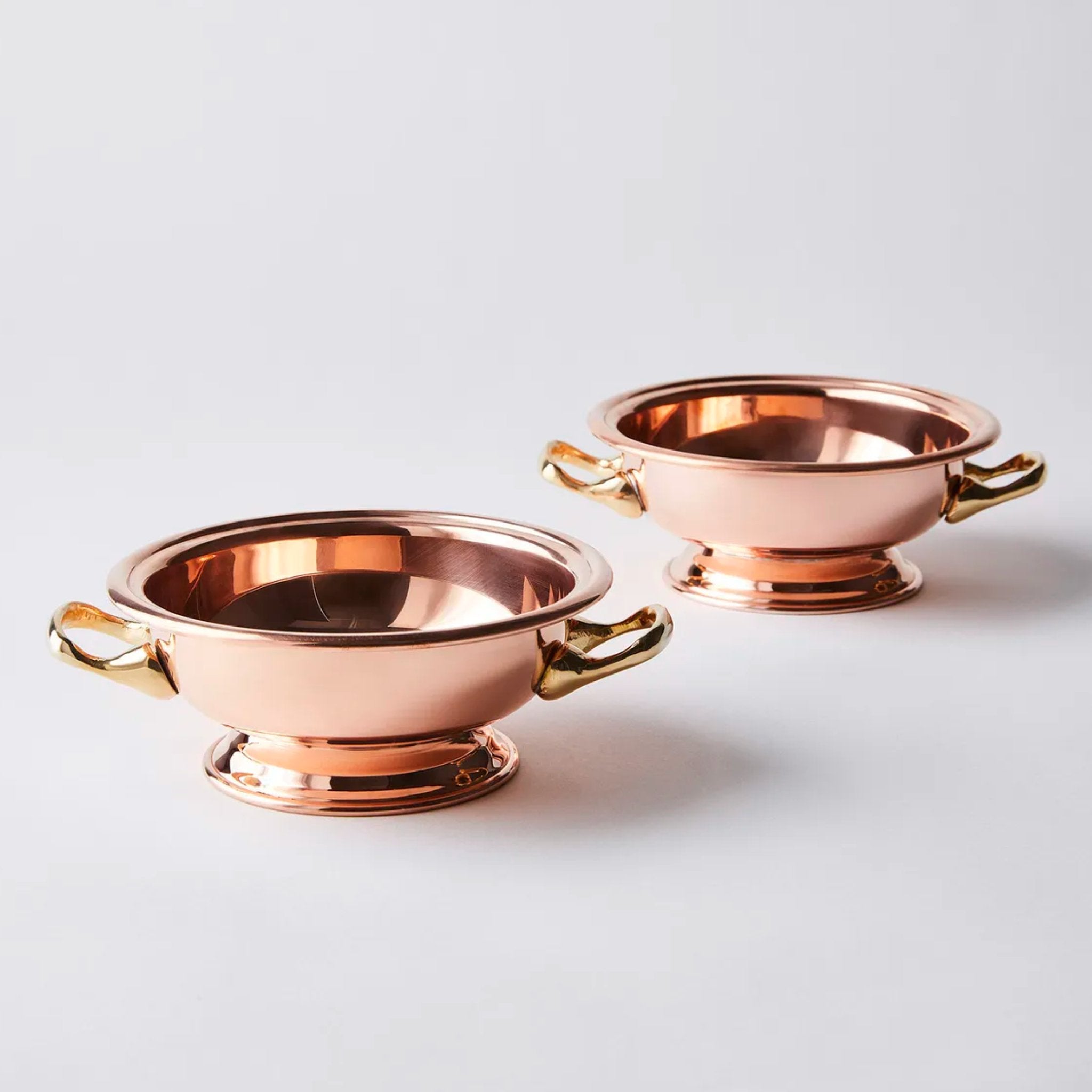 Pair of antique-inspired copper bowls on wooden surface