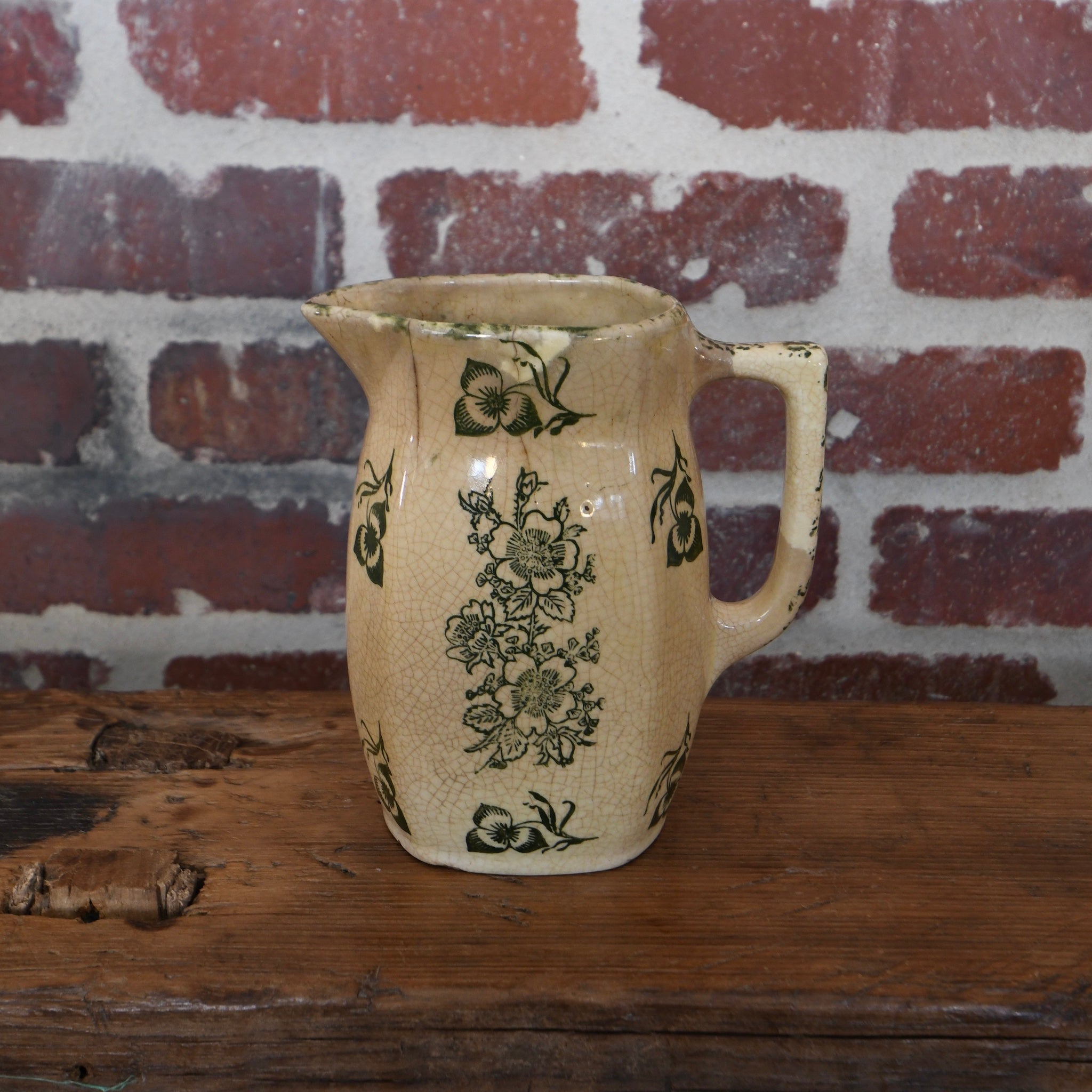 Antique saffron ceramic pitcher with olive green floral pattern, aged patina, and visible cracks and crazing, perfect for rustic or vintage-style décor.