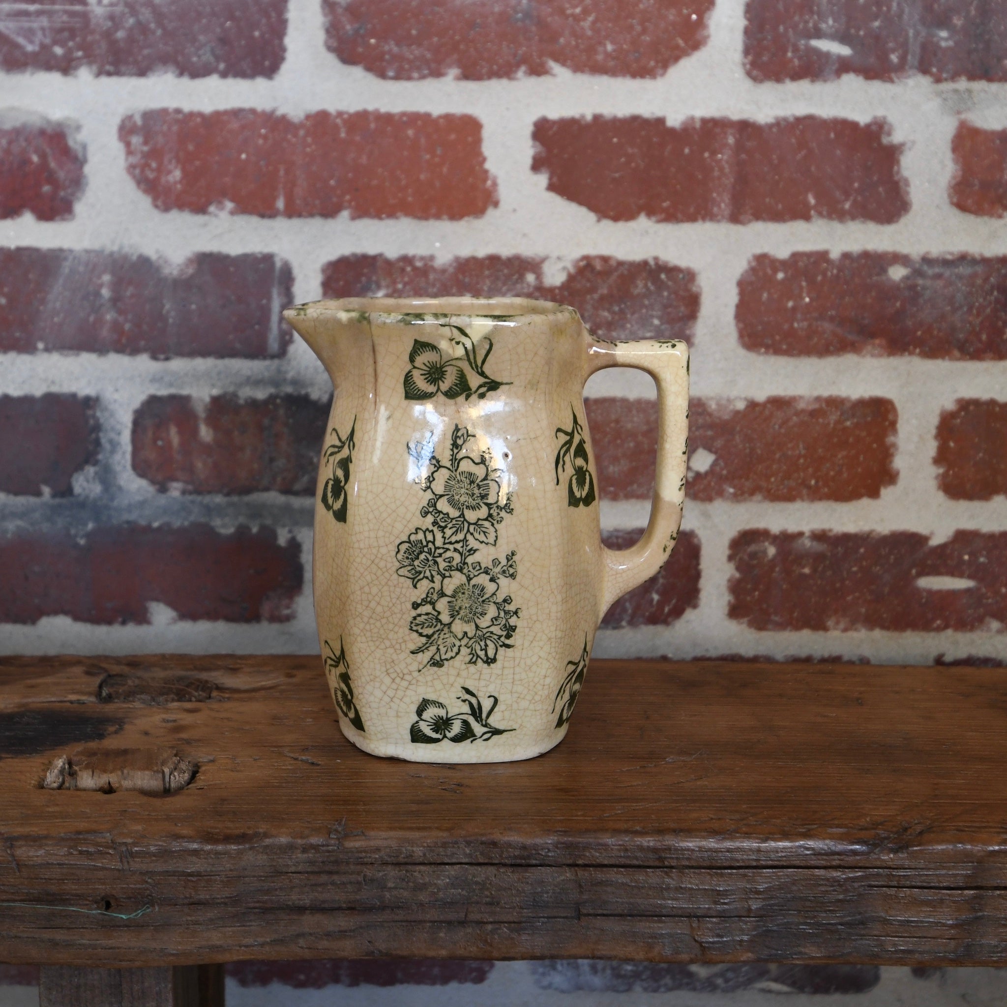 Antique saffron ceramic pitcher with olive green floral pattern, aged patina, and visible cracks and crazing, perfect for rustic or vintage-style décor.