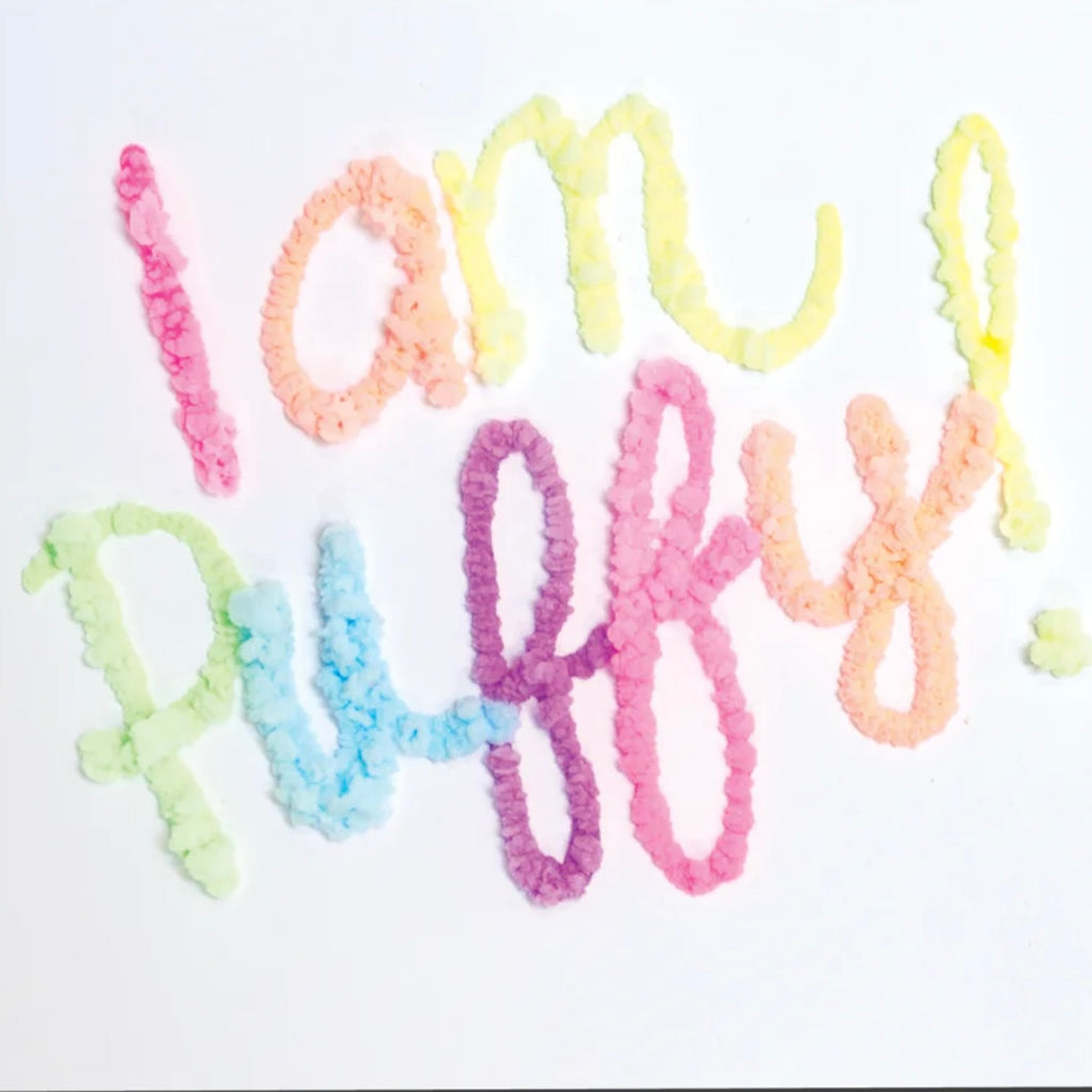 Colorful rice puffs arranged to spell "i am truly happy" on a white background using OOLY Magic Puffy Pens.