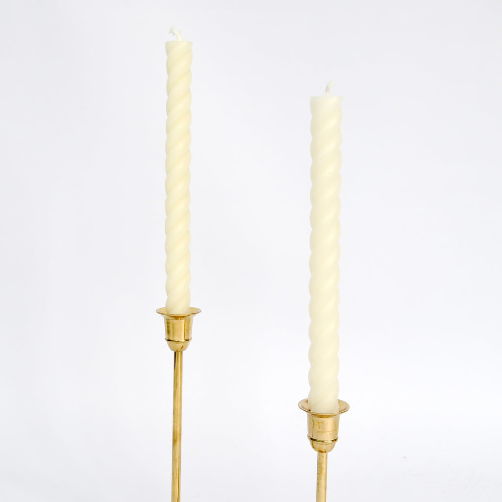 Two unlit twisted Rope Candles- Cream in brass holders against a white background by Greentree Home.
