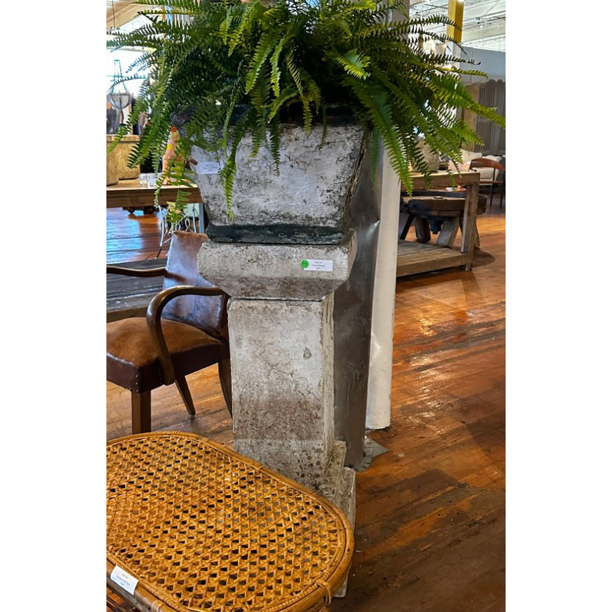 "Stone Pedestal Planter filled with vibrant flowers in a garden"