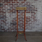 Decorative stand with gold accents against a brick wall