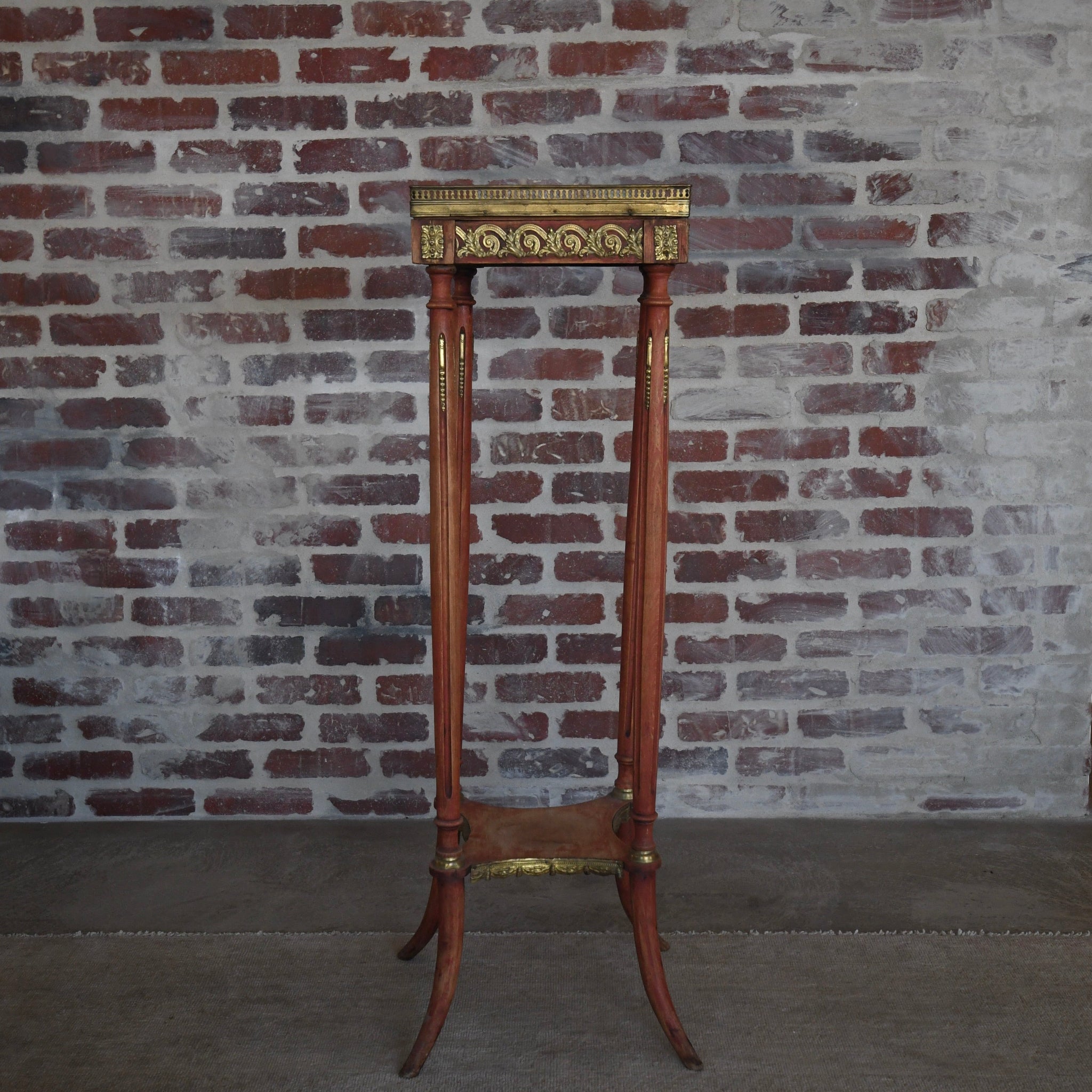 Decorative stand with gold accents against a brick wall