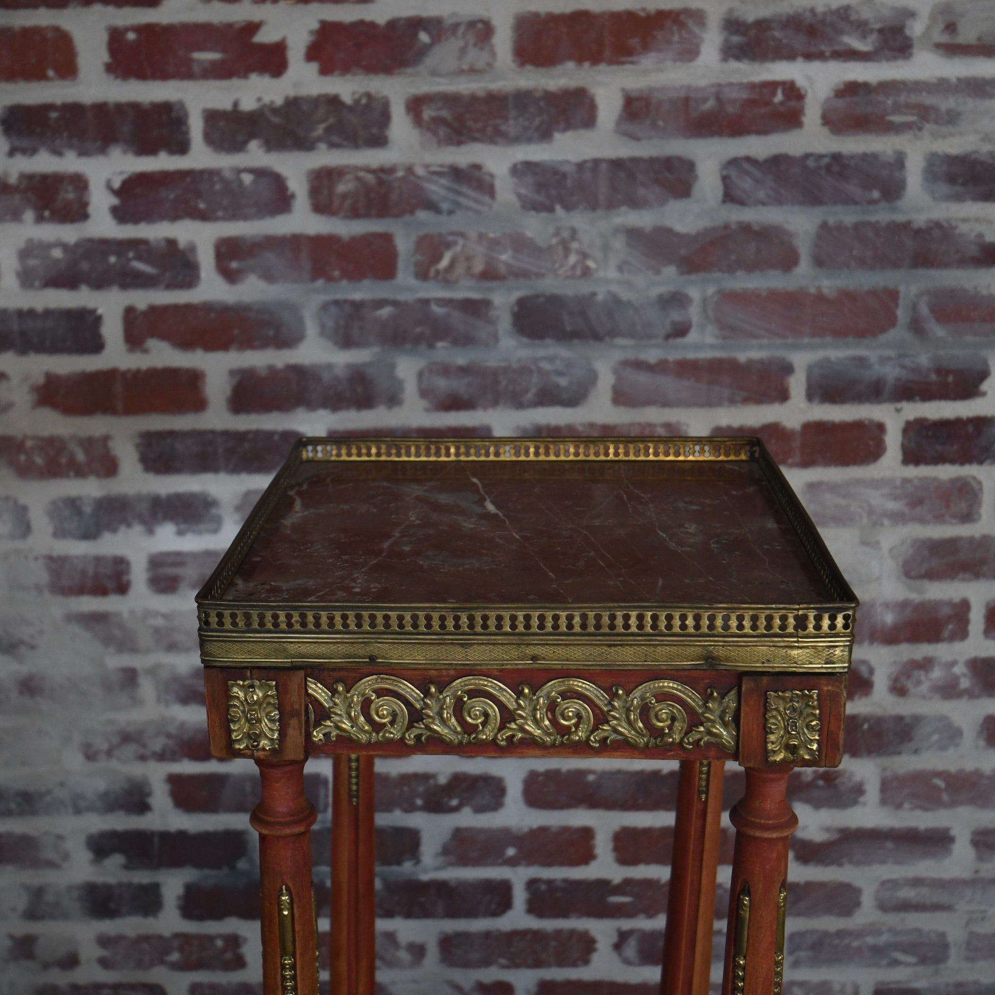 Decorative table with gold accents against a brick wall
