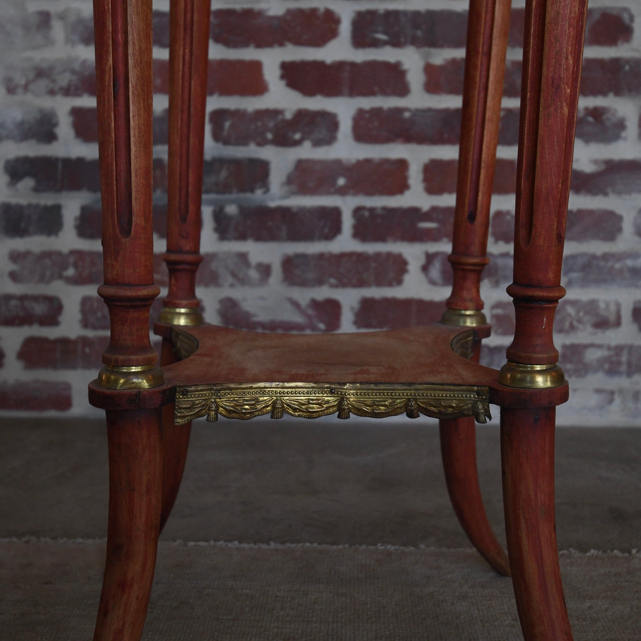 Wooden pedestal with gold accents against a brick wall.